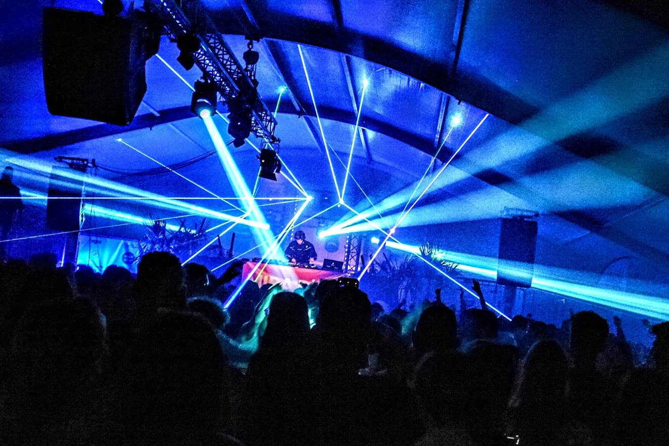 Photo of DJ LOST in front of an audience with blue laser beams in the picture.