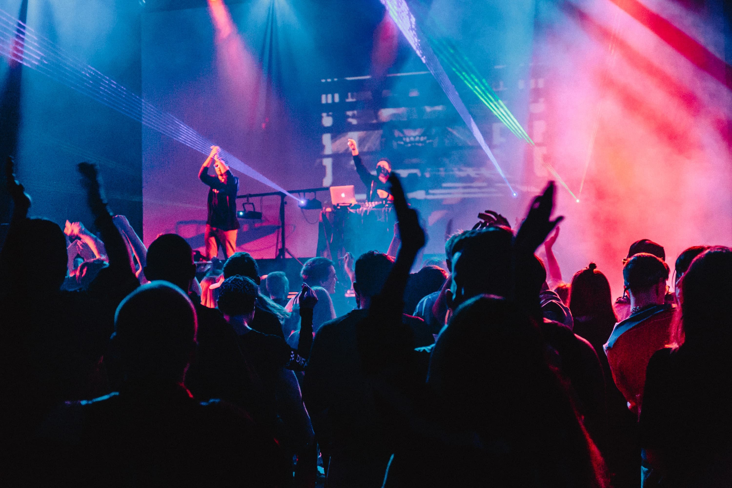 A picture showing a DJ in front of a dancing audience.
